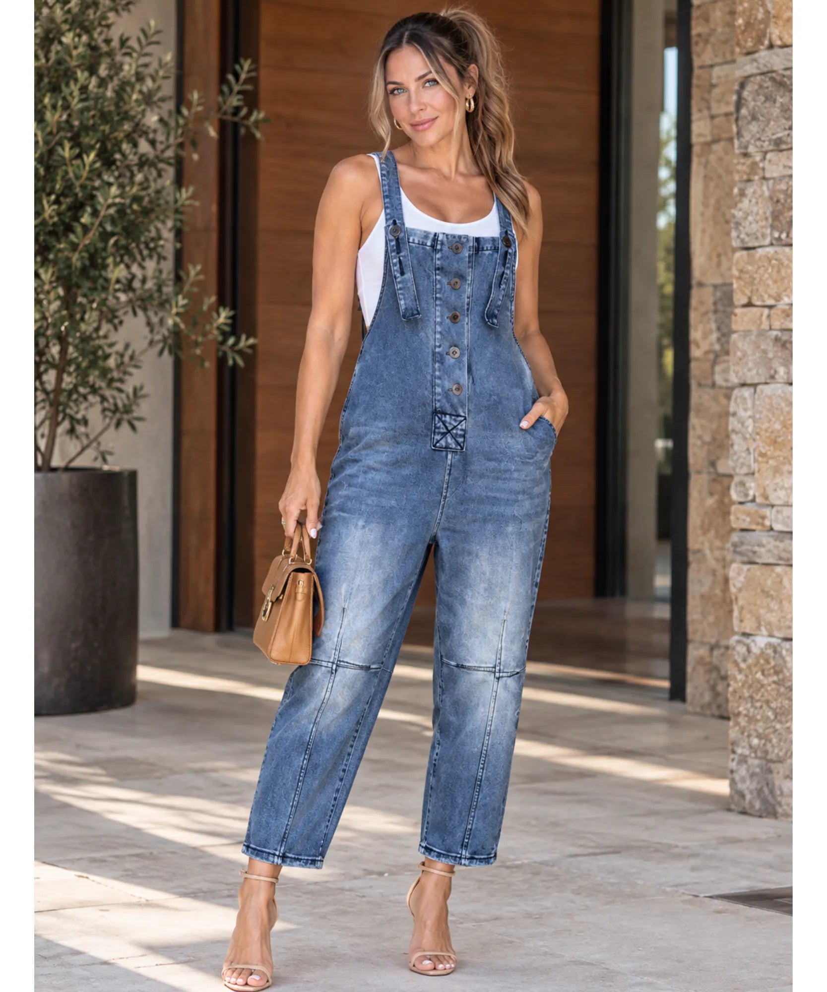 Jardineira jeans feminina azul escuro oversized combinada com bolsa de mão