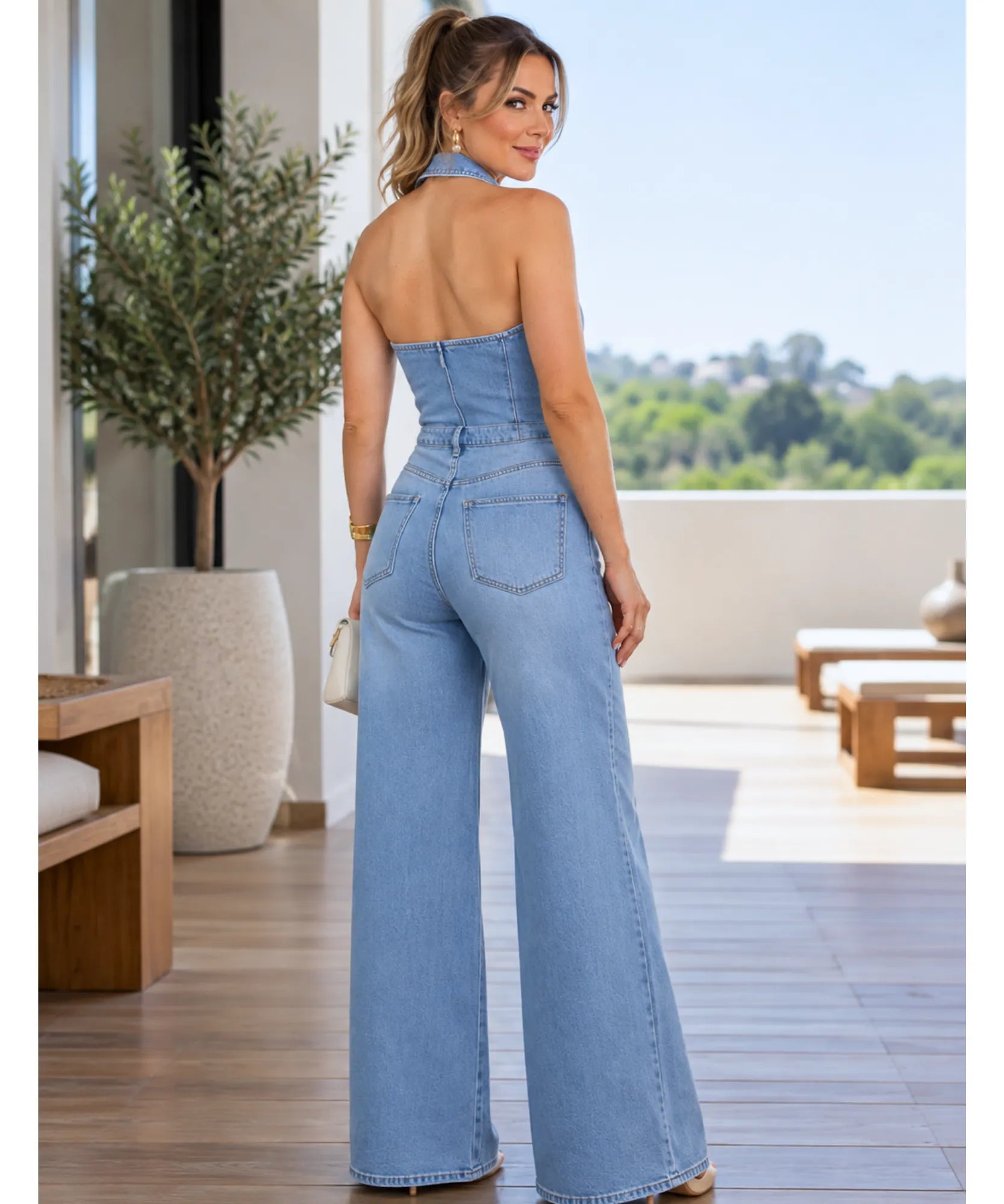Macacão jeans pantalona feminino azul claro visto de costas, com decote nas costas e alças finas