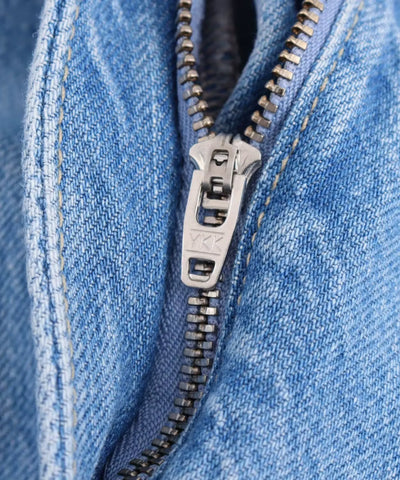 Detalhe macro do zíper frontal com ferragem YKK do macacão jeans pantalona feminino azul claro