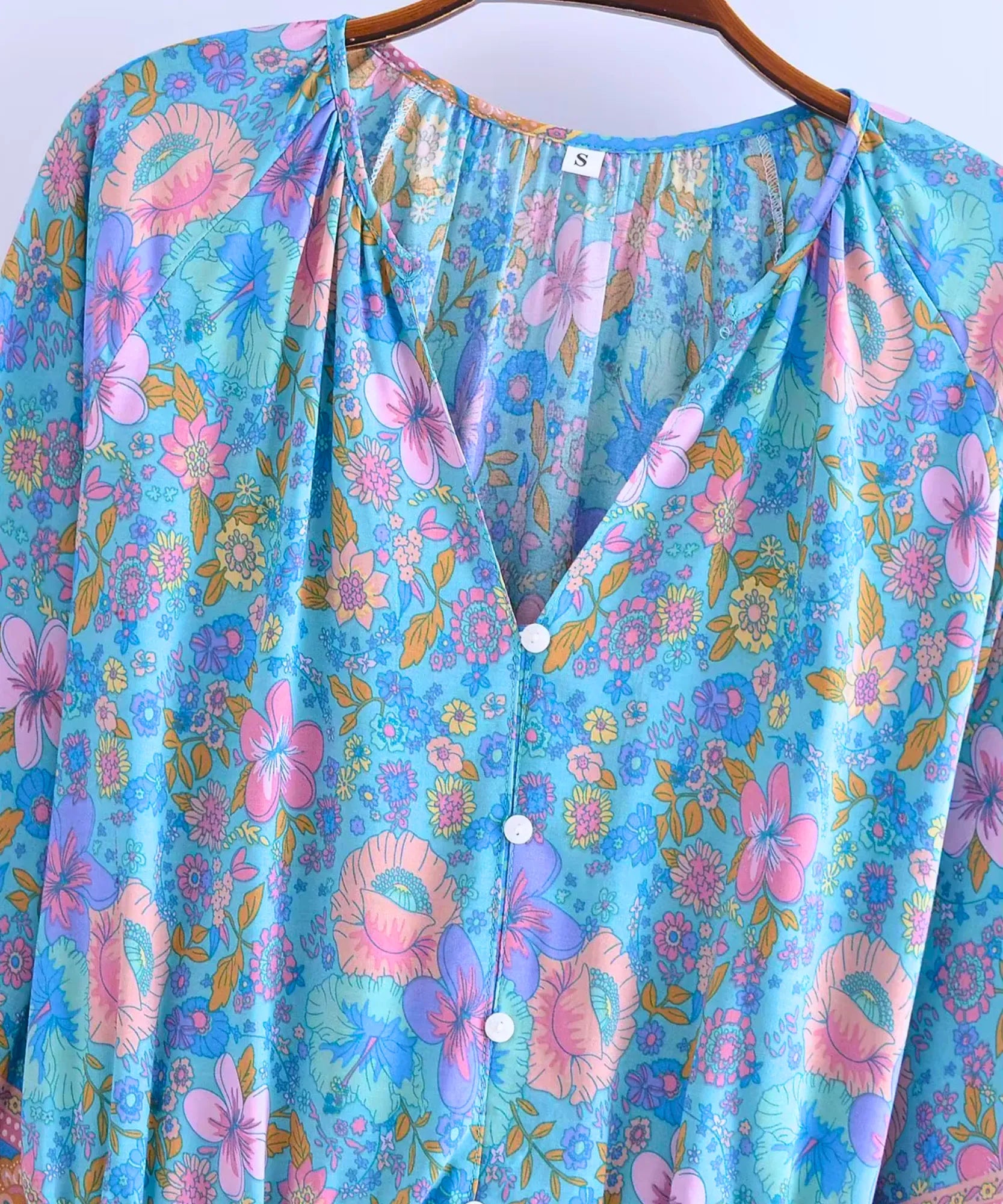 Detalhe do decote V do macaquinho feminino azul floral estampado