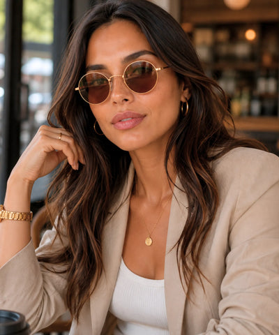 Modelo usando óculos de sol redondo feminino dourado com lente café e blazer bege em look casual chique | Allore Anellimn