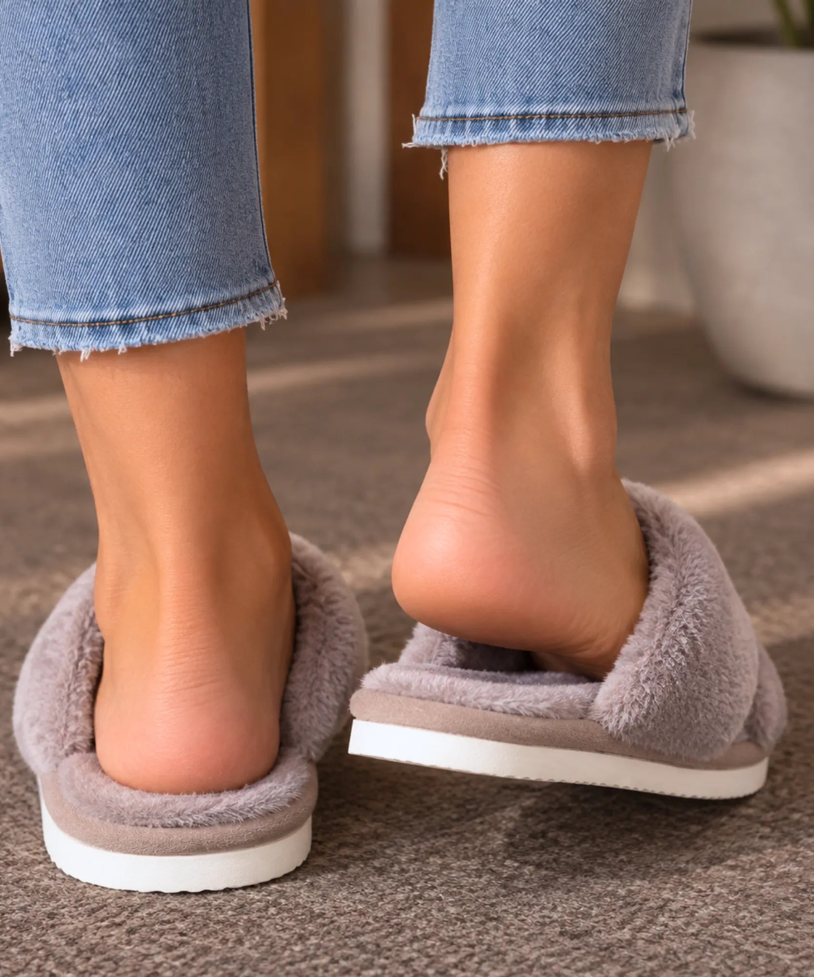 Calcanhar aberto e solado da pantufa aberta feminina de pelúcia cinza, vista de costas