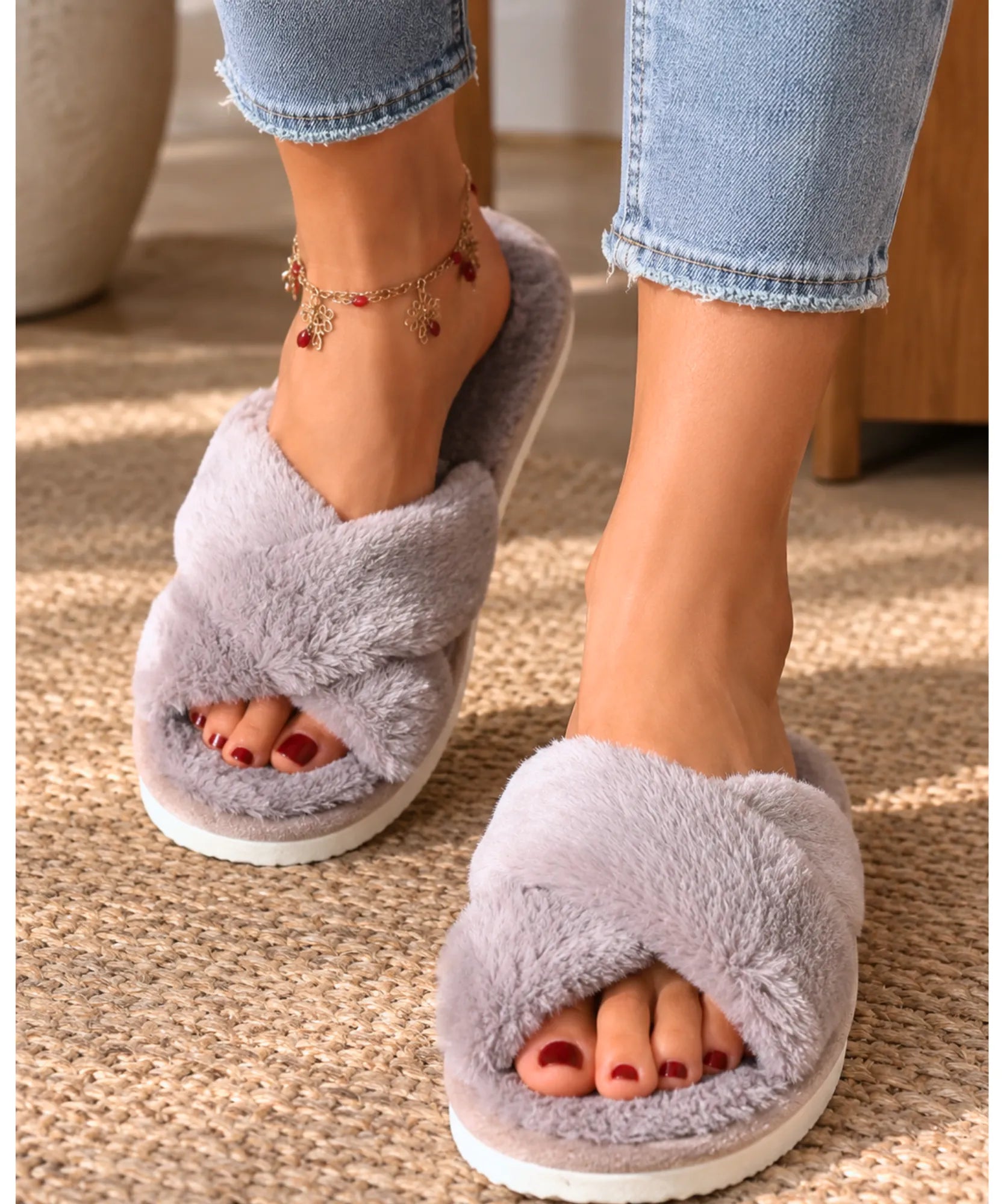 Pantufa aberta feminina de pelúcia cinza com tiras cruzadas, vista de frente nos pés