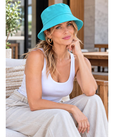 Chapéu bucket de algodão em tom turquesa, modelo sentada em ambiente externo