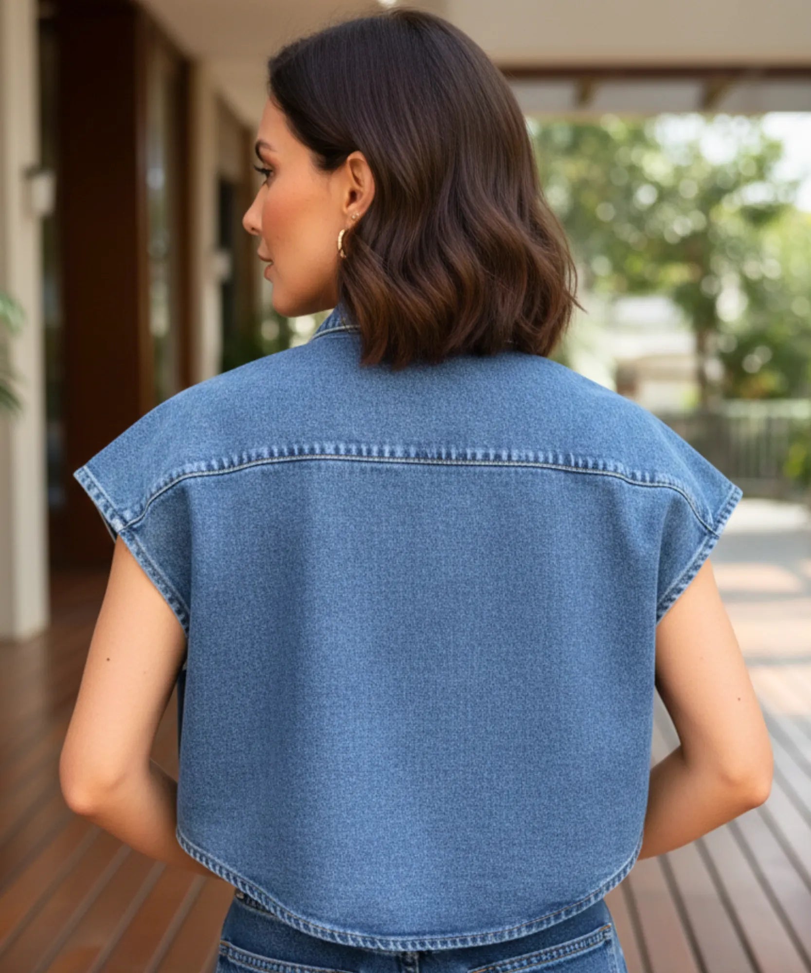 Costas do colete jeans feminino curto azul, com ombro caido e barra reta