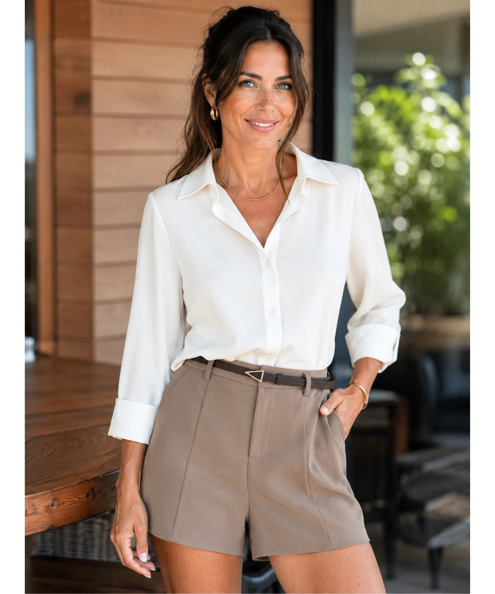 Modelo usando shorts de alfaiataria marrom taupe com camisa branca de manga longa em look de escritório