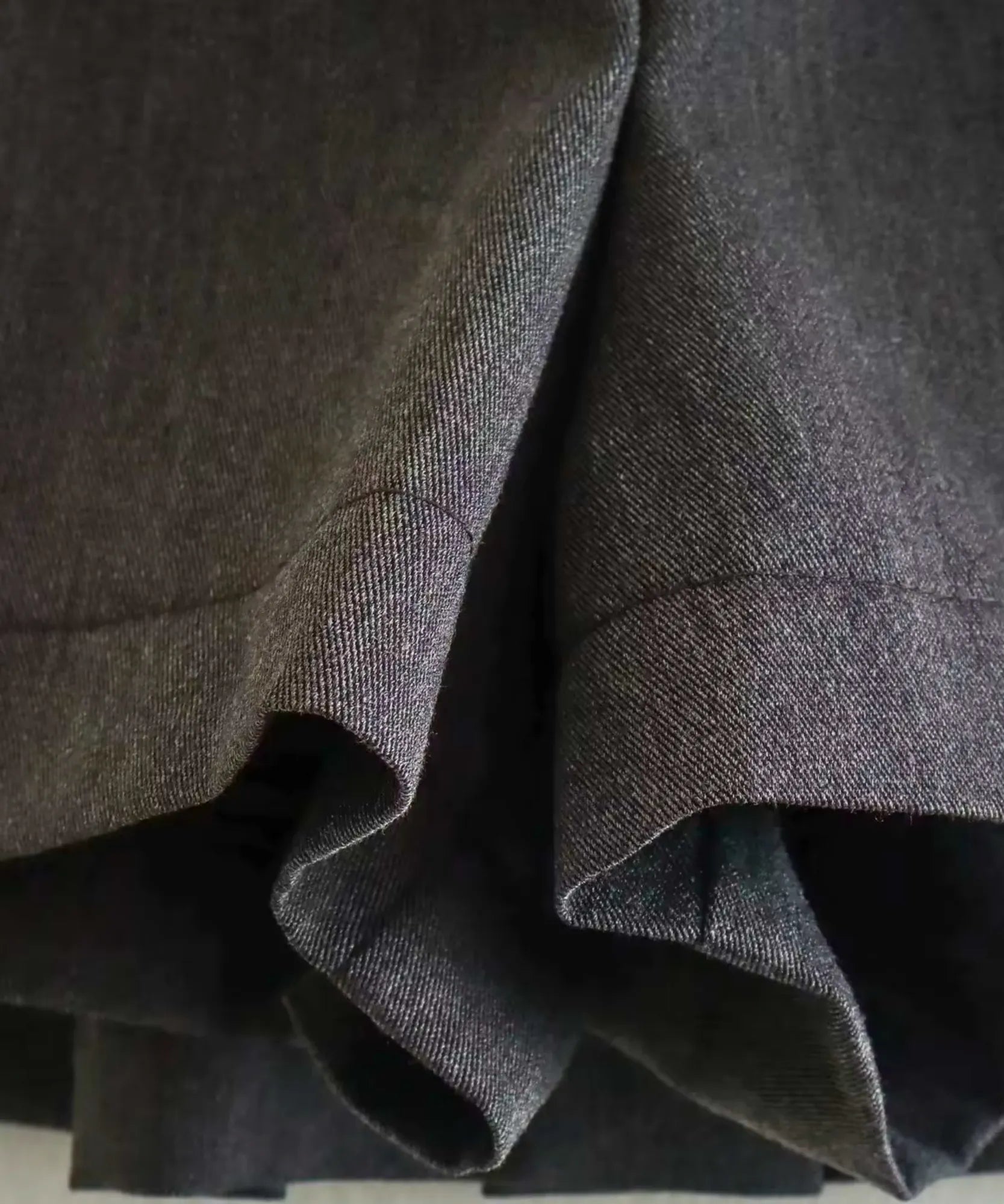 Detalhe das pregas estruturadas do shorts saia preto alfaiataria