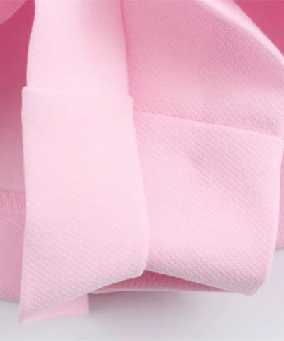 Detalhe macro do tecido texturizado em relevo e do laço costurado do shorts saia rosa - Anellimn Alisso