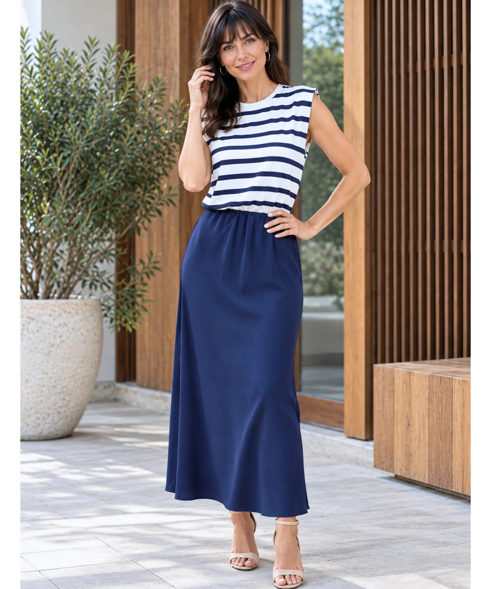 Vestido midi listrado azul marinho, modelo de frente com a mão no cabelo